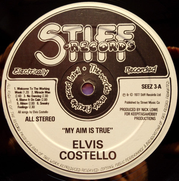 Image of Label Cover of LP - VG/G - ELVIS COSTELLO, My Aim Is True (Stiff Records; SEEZ 3, UK 1977, B&W Photo, Red Text, Purple Back), Light marks but lots of 'em. Black inner.,  - 4316179C